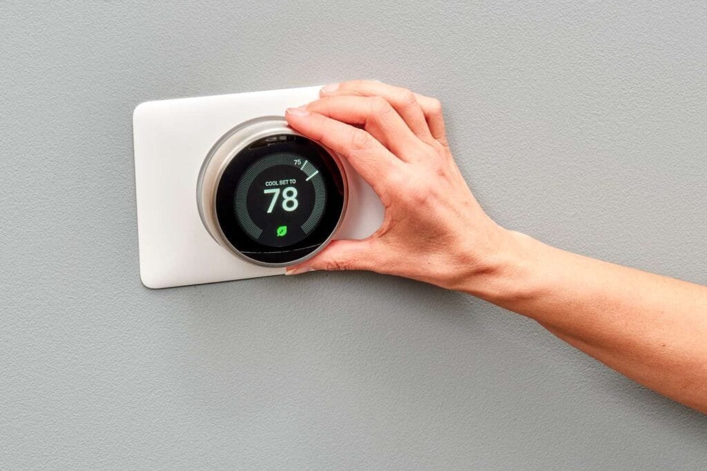 A digital smart thermostat mounted on a wall, showing temperature settings